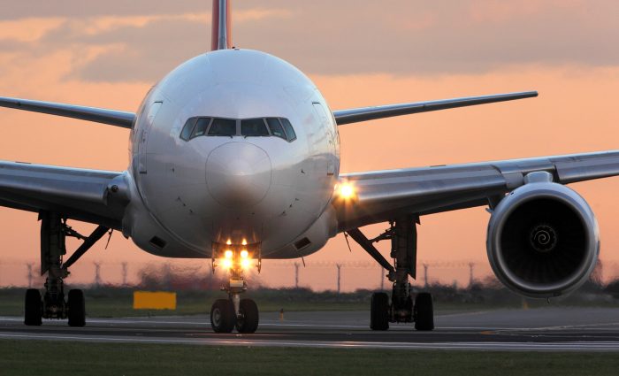 Modern civil passenger airliner taking off at airport during sunset.