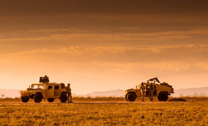 Soldiers patrolling on foot and escorted by a Humvee